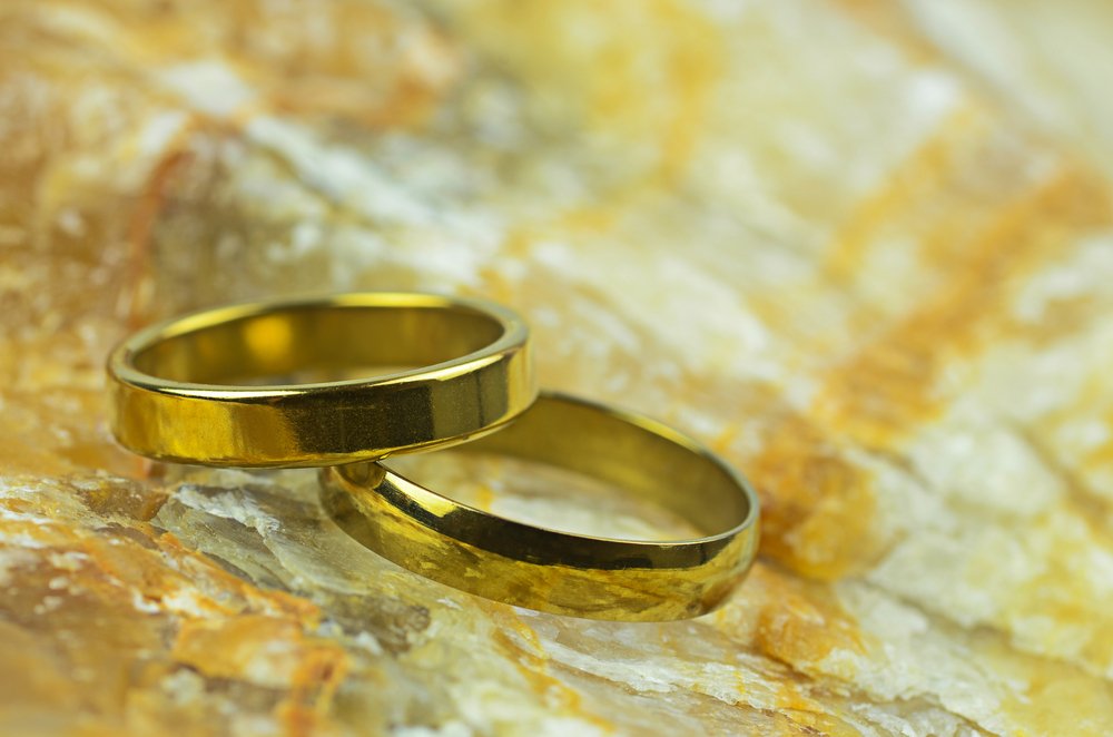 couple gold rings on marble stone