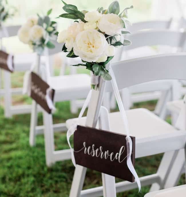 wood reserved seating sign hanging on white chair