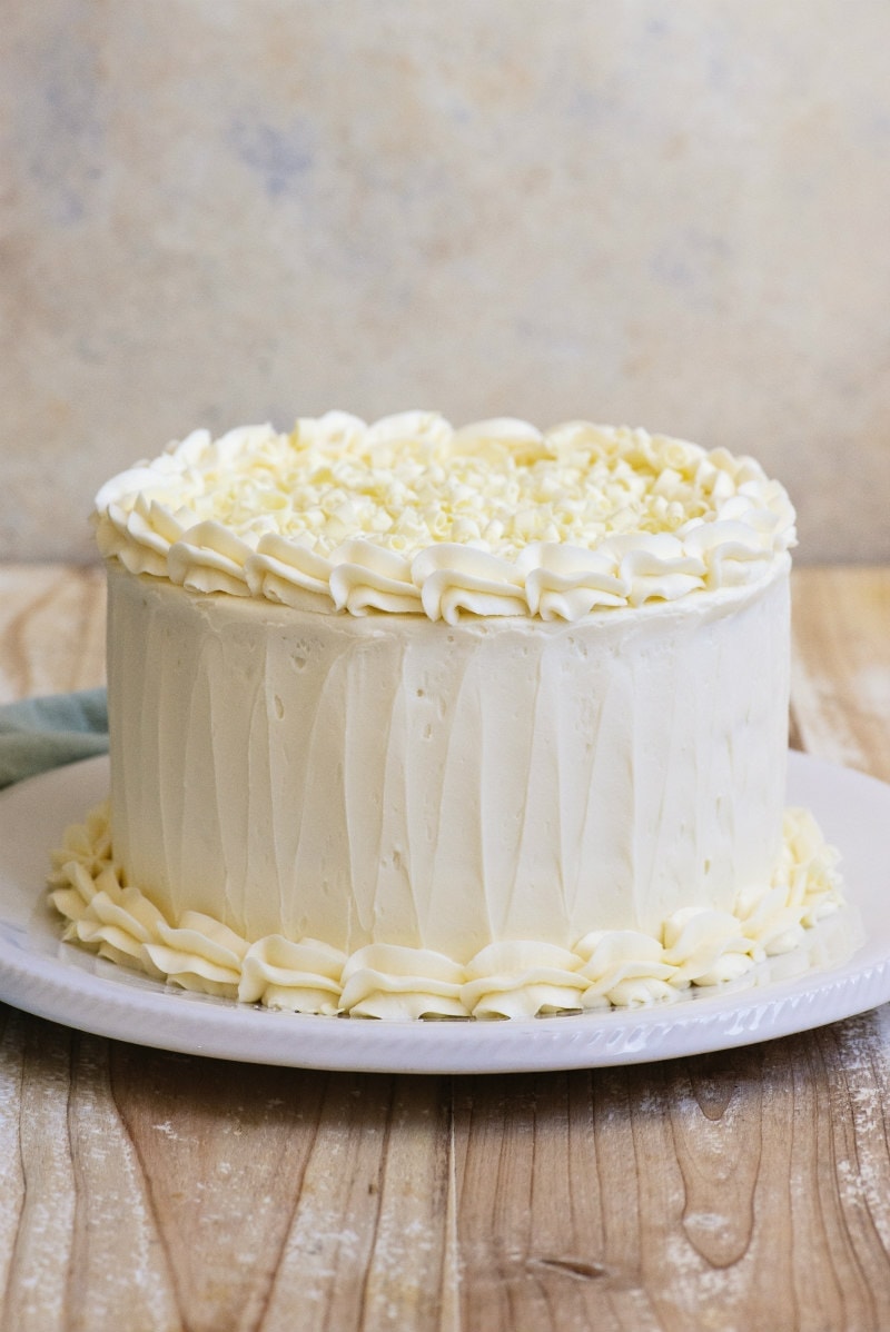 Easy White Wedding Cake recipe from RecipeGirl.com #easy #white #wedding #cake #recipe #RecipeGirl White Wedding Cake sitting on a white platter on a wooden board