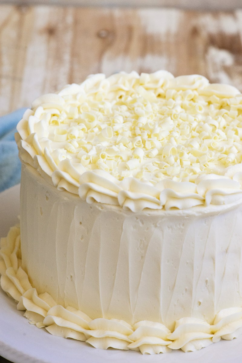 Easy White Wedding Cake recipe from RecipeGirl.com #easy #white #wedding #cake #recipe #RecipeGirl White Wedding Cake sitting on a white platter on a wooden board