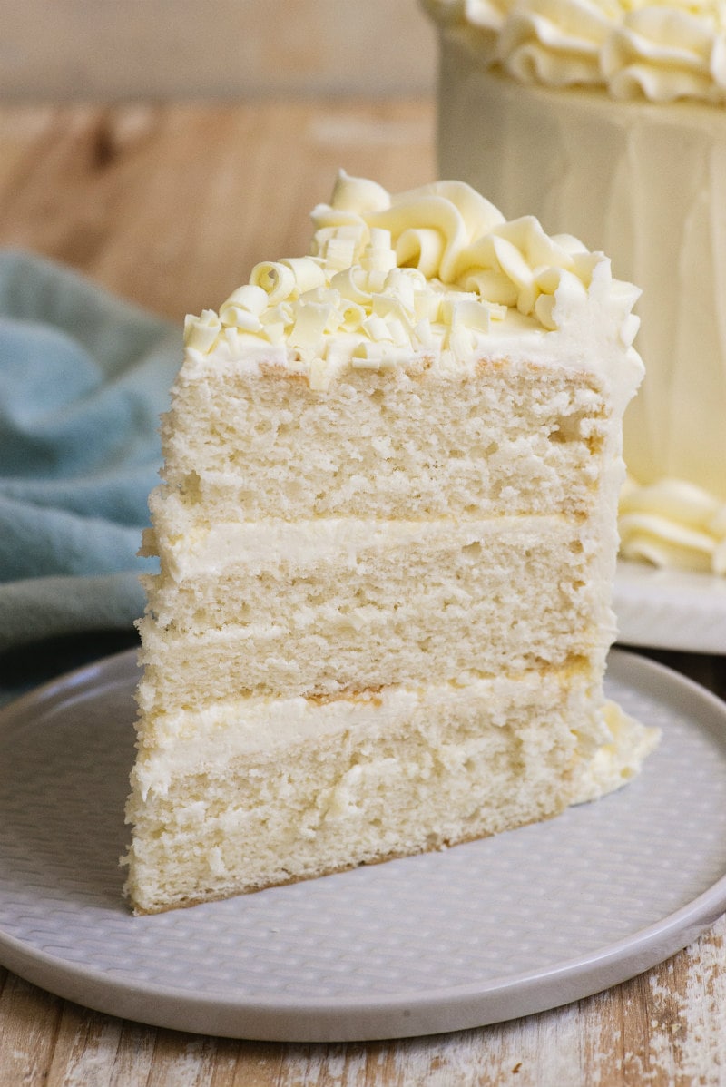 Easy White Wedding Cake recipe from RecipeGirl.com #easy #white #wedding #cake #recipe #RecipeGirl slice of three layer white wedding cake on a white plate
