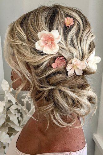 curly wedding hairstyles side low updo with culs with pink flowers hair and makeup girl via instagram