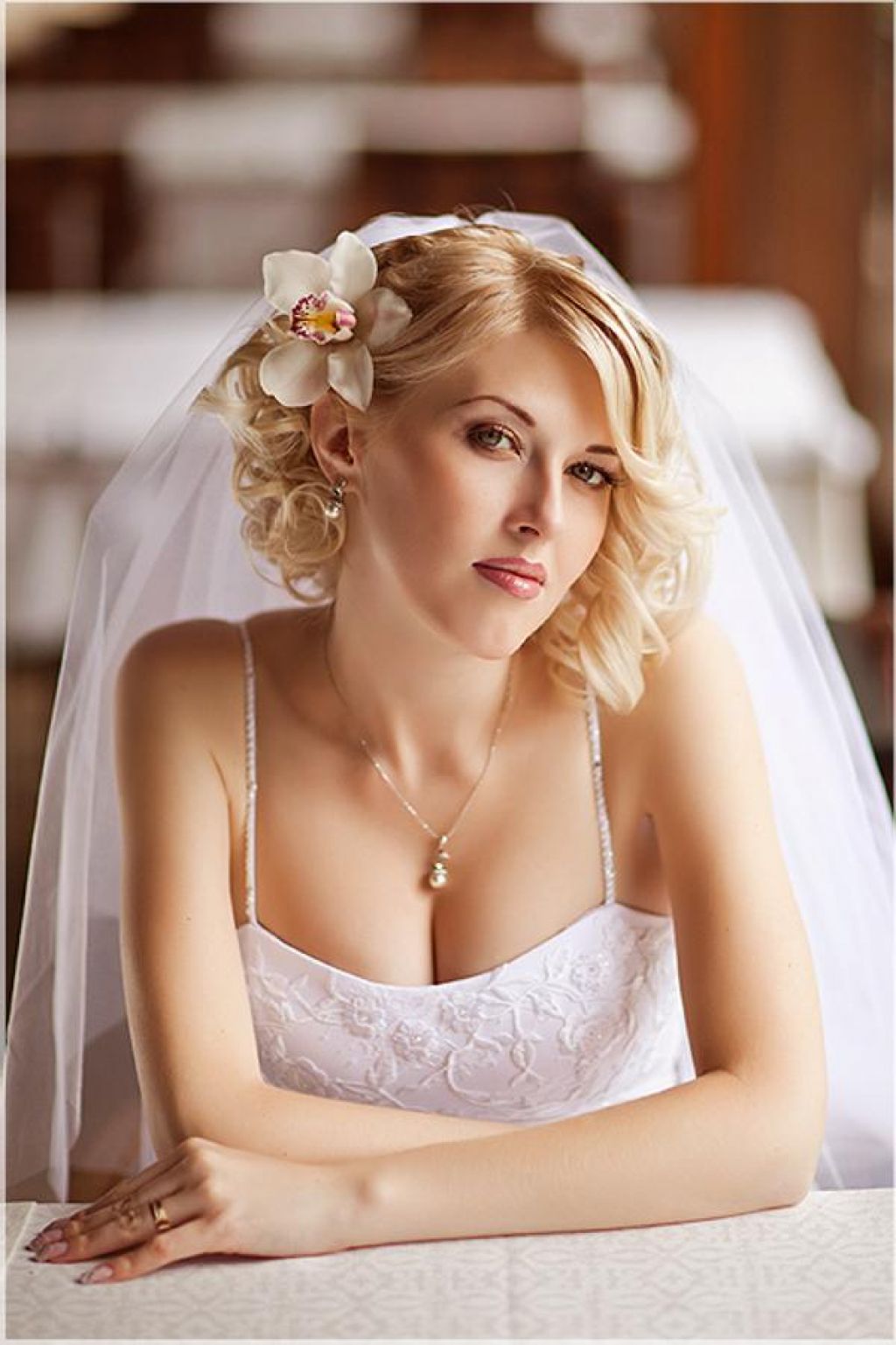 свадебная короткая причёска с фатой и с цветком сбоку в волосах.